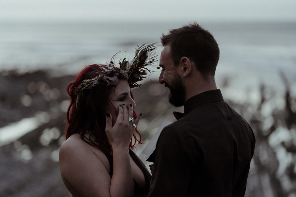 La mariée rock'n'roll avec sa robe de mariage noire pleure d'émotion. Elle essuie sa larme pendant la lecture de ses voeux de mariage à l'occasion de leur elopement dans les Pyrénées avec leur photographe Gaétane Glize.