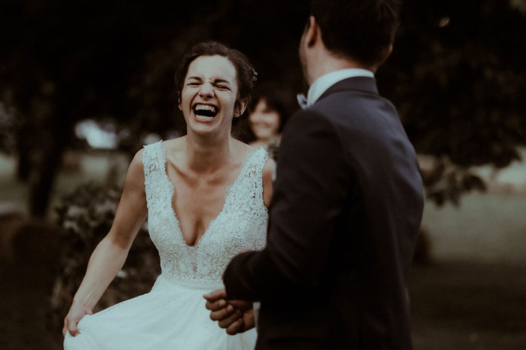 La mariée rigole à gorge déployée pendant le vin d'honneur de son mariage, un moment de joie photographié par Gaétane Glize, photographe mariage Dax.