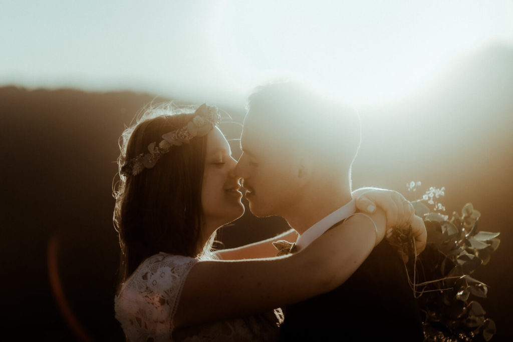 Un couple de mariés s'embrassent au coucher du soleil pendant leur séance photo elopement avec Gaétane Glize, photographe mariage Landes et Pays Basque.