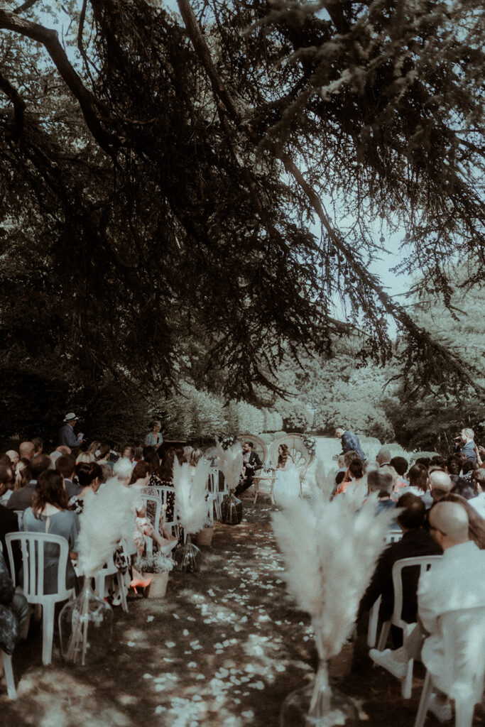 La cérémonie laïque de mariage se déroule dans les jardins d'un château sous des arbres centenaires.