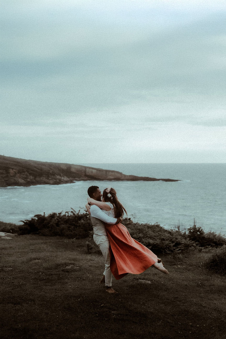 Un homme fait tourner sa femme sur les falaises qui surplombent l'océan à Biarritz au Pays Basque, un moment fun et amusant pendant leur séance photo couple pour célébrer leur PACS.