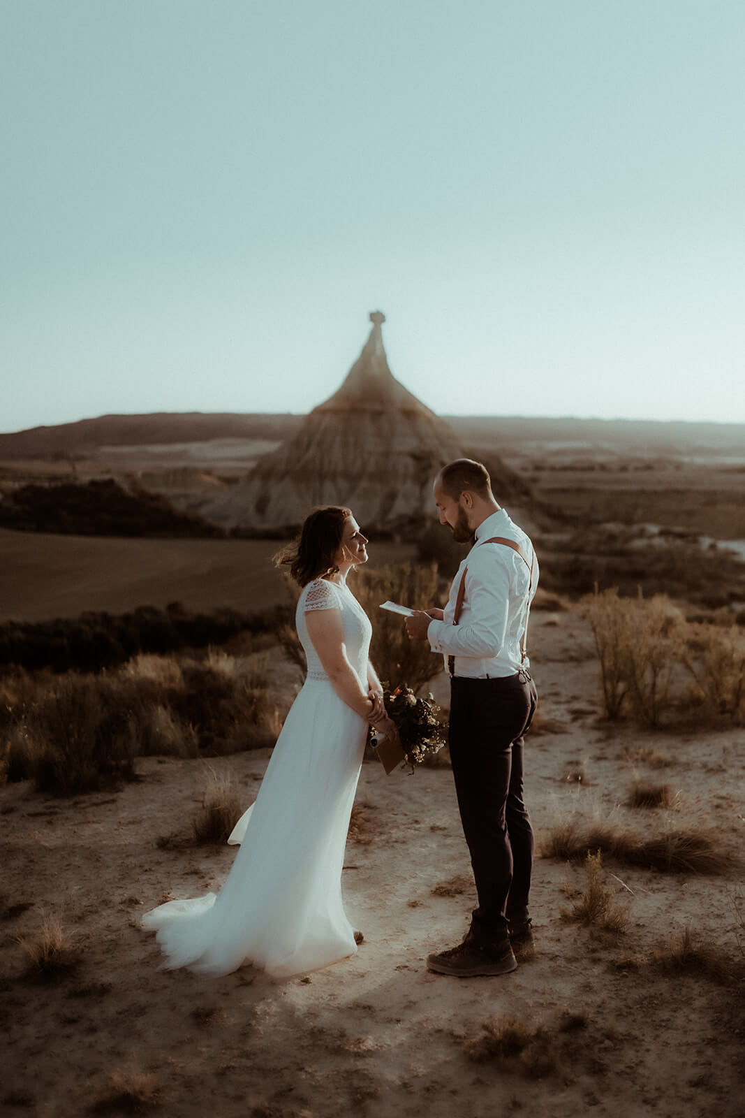 Un couple se lit une lettre d'amour pendant leur séance photo couple de mariage dans le désert des Bardenas Reales en Espagne.