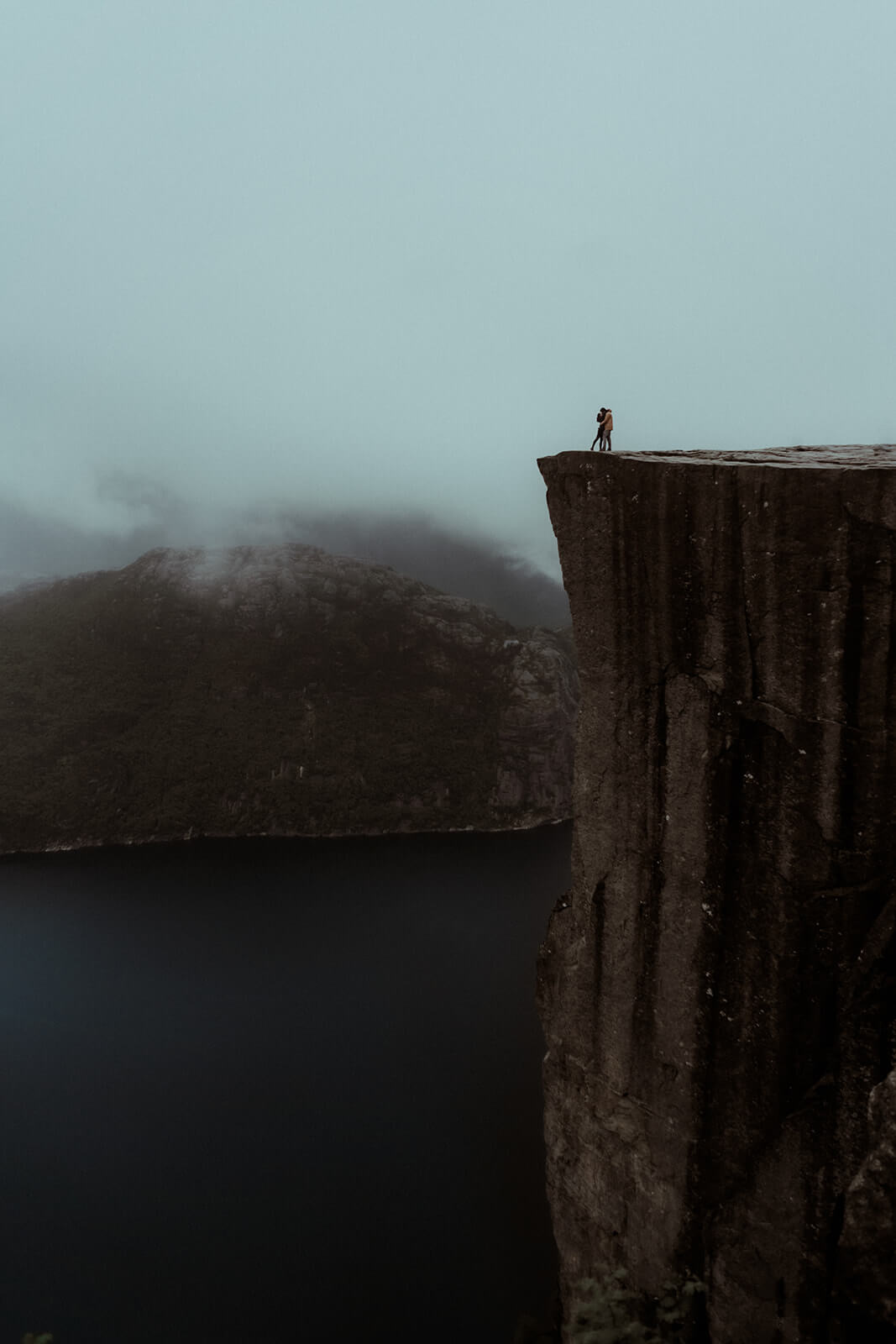 Un couple s'embrasse sur la falaise Preikestolen ou Pulpit Rock du fjord en Norvège. Une séance photo de couple faite par Gaétane Glize.