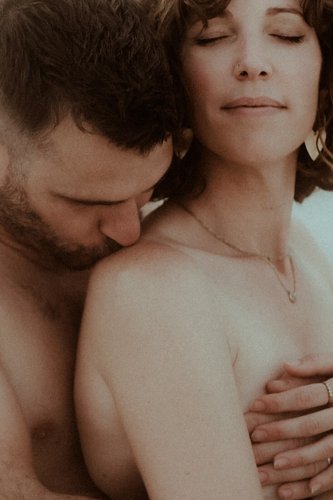 Un homme embrasse tendrement l'épaule de sa femme. Un moment de douceur pendant leur séance photo couple pour célébrer leur anniversaire de mariage avec Gaétane Glize, photographe couple landes.