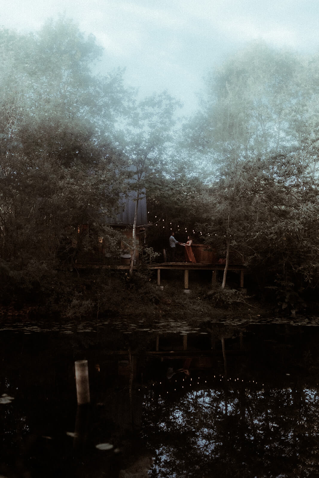 Un couple danse sur la terrasse de la cabane en bois Landifornia à Hossegor, elle se trouve dans la forêt au bord d'un étang. Un moment capturé par Gaétane Glize, photographe couple landes.