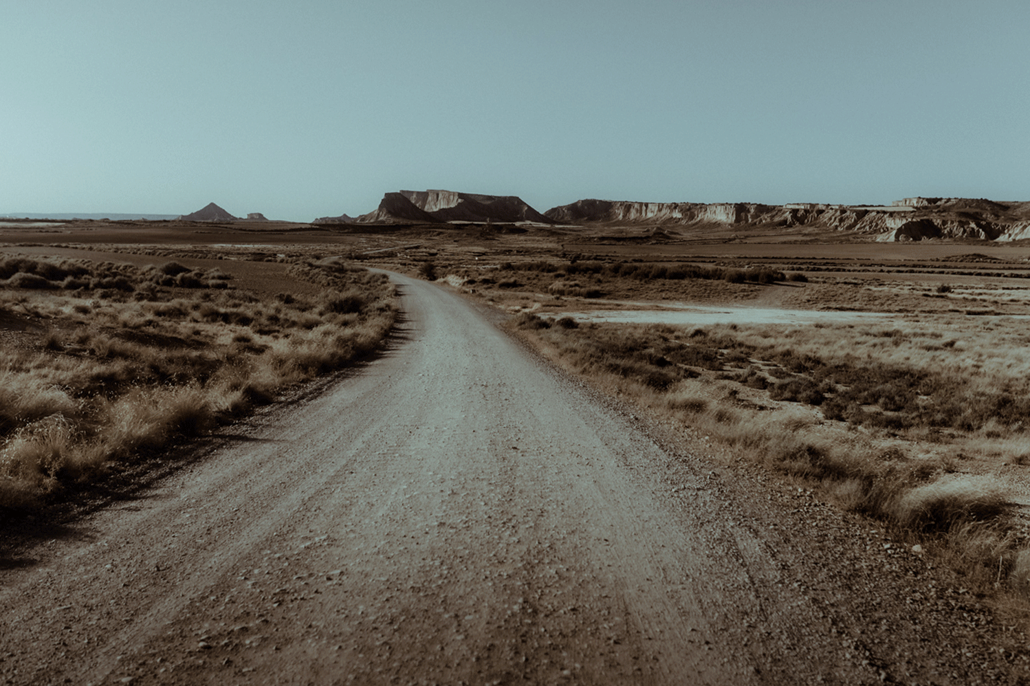 Un couple de mariés courent main dans la main dans le desert des Bardenas en Espagne ou ils ont fait un roadtrip pour célébrer leur mariage en faisant un elopement.