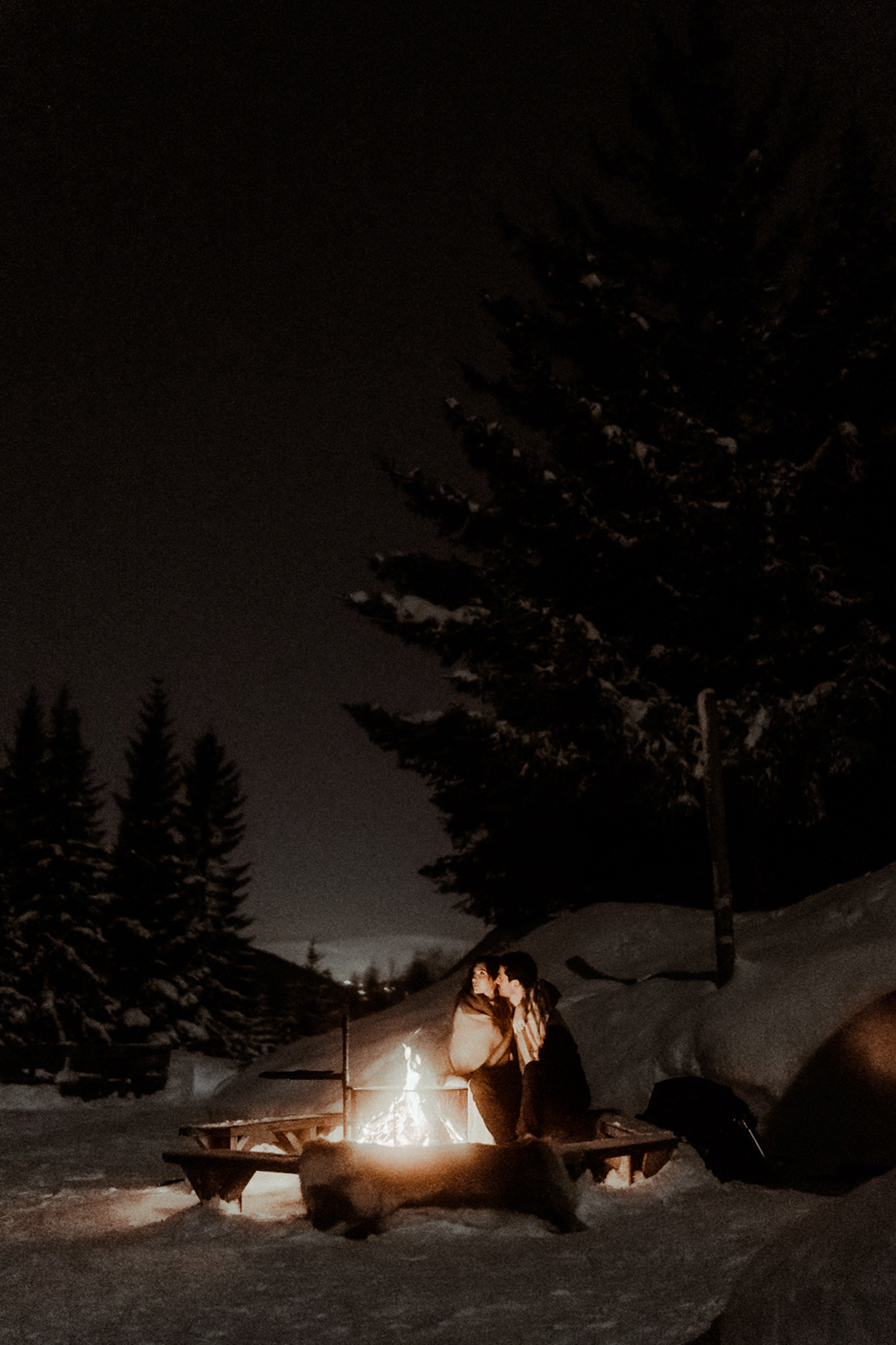 Un couple de mariés sont assis au bord d'un feu de camp de nuit sous le ciel étoilé. Ils célèbrent leur mariage avec Gaétane Glize, photographe elopement Pyrénées.